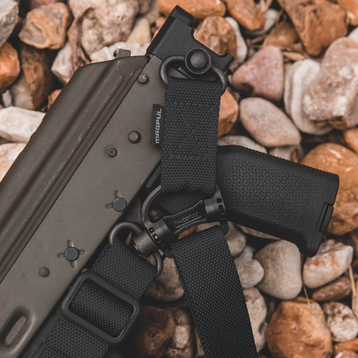Magpul MS4 Dual QD Sling GEN2 – One & Two Point Rifle Sling, attached to a rifle laid on gravel