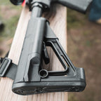 Magpul STR Carbine Stock Mil-Spec for AR-15/M4, on a rifle resting on a wooden rail
