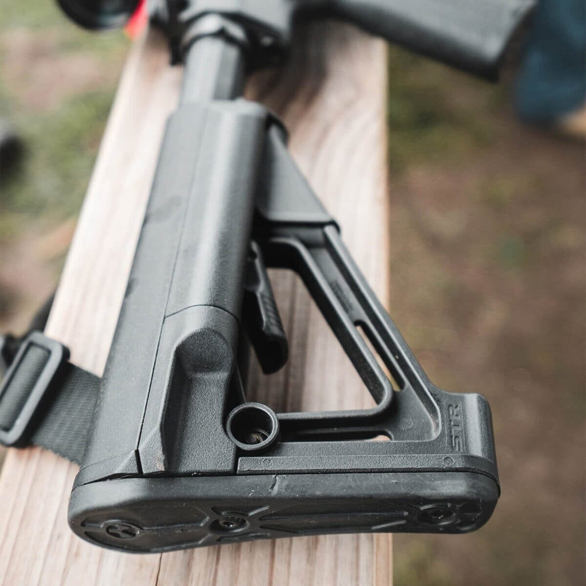 Magpul STR Carbine Stock Mil-Spec for AR-15/M4, on a rifle resting on a wooden rail